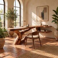 Freeform slab desk on a twisting root shaped base with an open side shelf in a bright home office with arched windows and plants