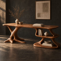 Corner detail of desk with a root shaped leg and an open shelf pedestal beside wood, brass and linen samples