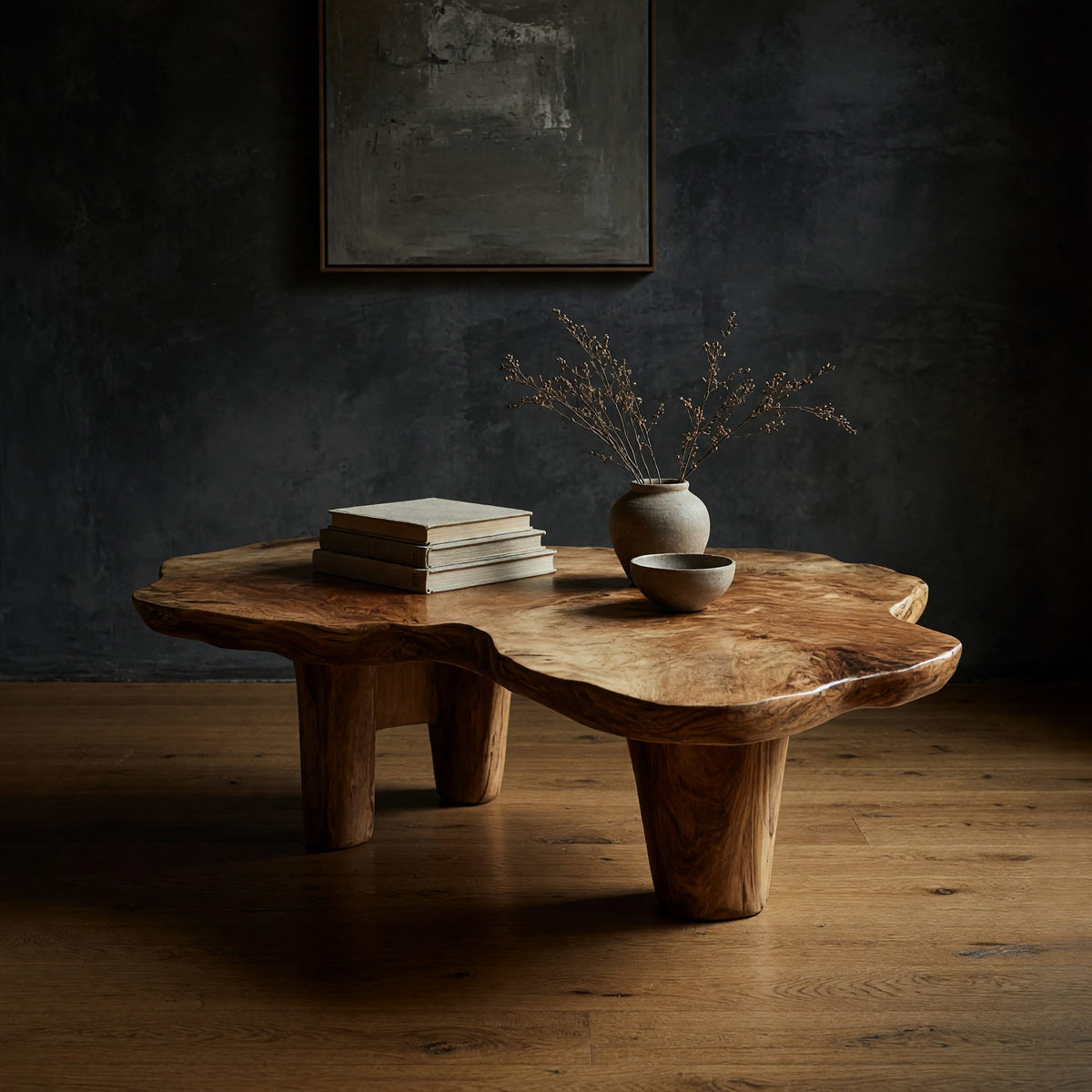 Free form live edge low table on stump legs in a dark studio against a charcoal wall
