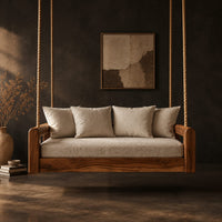Rope hung swing with open frame arms and a deep seat cushion in a dark studio against a charcoal plaster wall