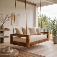 Rope hung swing with open frame arms and a deep seat cushion in a Scandinavian porch with white walls