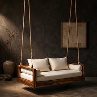 Wooden swing hung from four thick ropes with a low solid wood frame in a dark studio against a charcoal plaster wall