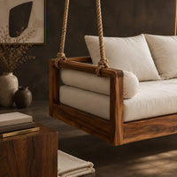Corner detail of wooden swing hung from four thick ropes with a low solid wood frame beside wood, brass and linen samples