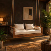 Wooden swing hung from four thick ropes with a low solid wood frame in a dark porch at golden hour