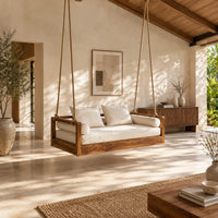 Wooden swing hung from four thick ropes with a low solid wood frame in a bright open plan porch