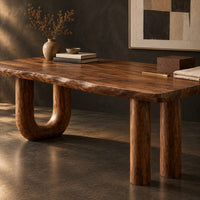 Corner detail of plank top desk with a u shaped leg and two column legs beside wood, brass and linen samples