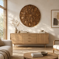 Round carved flower medallion with layers of overlapping petals above a light oak sideboard in daylight