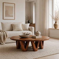 Round coffee table with a wide flat top on chunky v shaped legs in a Scandinavian living room with white walls