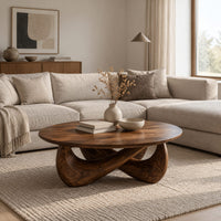 Round coffee table with a thin top and a crossed sculpted base in a Scandinavian living room with white walls
