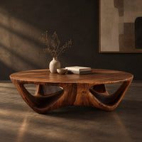 Round coffee table with a flared sculpted base and scooped arch openings, three-quarter view showing the grain