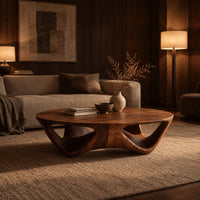Round coffee table with a flared sculpted base and scooped arch openings in an evening living room with walnut wall paneling