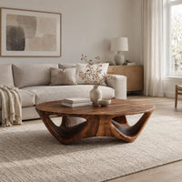 Round coffee table with a flared sculpted base and scooped arch openings in a Scandinavian living room with white walls