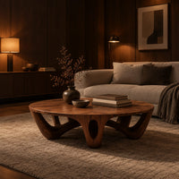 Round coffee table with arched sculpted legs and oval openings in an evening living room with walnut wall paneling