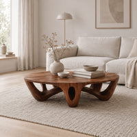Round coffee table with arched sculpted legs and oval openings in a Scandinavian living room with white walls