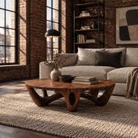 Round coffee table with arched sculpted legs and oval openings in an industrial loft living room with exposed brick