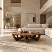 Round coffee table with arched sculpted legs and oval openings in a bright open plan living room