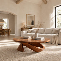 Round coffee table with a cone foot and a tilted open loop base in a bright open plan living room