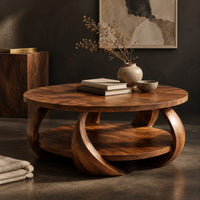 Corner detail of round coffee table with crescent shaped legs and a round lower shelf beside wood, brass and linen samples