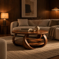 Round coffee table with crescent shaped legs and a round lower shelf in an evening living room with walnut wall paneling