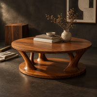 Corner detail of circular coffee table with flared legs standing on a low base disc beside wood, brass and linen samples