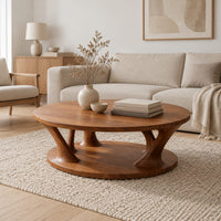 Circular coffee table with flared legs standing on a low base disc in a Scandinavian living room with white walls