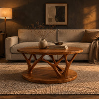 Circular coffee table with forked antler shaped legs above a wide disc base in a dark living room at golden hour