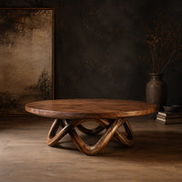 Round coffee table with a thick top and an interlaced looping wood base in a dark studio against a charcoal plaster wall