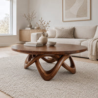 Round coffee table with a thick top and an interlaced looping wood base in a Scandinavian living room with white walls