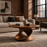 Round coffee table on a looping ribbon base in an industrial loft living room with exposed brick