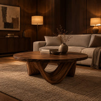 Round coffee table with a low swooping arch base in an evening living room with walnut wall paneling
