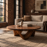 Round coffee table with a low swooping arch base in an industrial loft living room with exposed brick