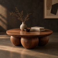 Round coffee table with a thick top resting on three large wooden balls, three-quarter view showing the grain