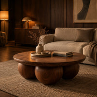 Round coffee table with a thick top resting on three large wooden balls in an evening living room with walnut wall paneling