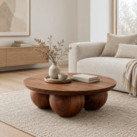 Round coffee table with a thick top resting on three large wooden balls in a Scandinavian living room with white walls