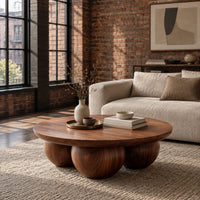 Round coffee table with a thick top resting on three large wooden balls in an industrial loft living room with exposed brick
