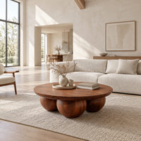 Round coffee table with a thick top resting on three large wooden balls in a bright open plan living room