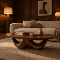 Round coffee table with a thick top on a sculpted base with two arches in an evening living room with walnut wall paneling