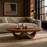 Round coffee table with a thick top on a sculpted base with two arches in an industrial loft living room with exposed brick