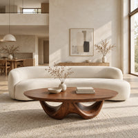 Round coffee table with a thick top on a sculpted base with two arches in a bright open plan living room