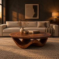 Round coffee table with a wavy ribbon base and swirled wood grain in a dark living room at golden hour