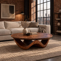 Round coffee table with a wavy ribbon base and swirled wood grain in an industrial loft living room with exposed brick