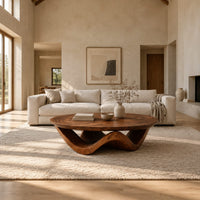 Round coffee table with a wavy ribbon base and swirled wood grain in a bright open plan living room