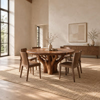 Round dining table with a carved tree trunk base and a grained top in a bright open plan dining room