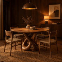 Round dining table on a sculpted base of two crossing wooden loops in an evening dining room with walnut wall paneling