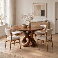 Round dining table on a sculpted base of two crossing wooden loops in a Scandinavian dining room with white walls