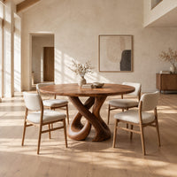 Round dining table on a sculpted base of two crossing wooden loops in a bright open plan dining room