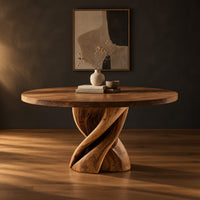 Round dining table with a twisted ribbon pedestal in a dark studio against a charcoal plaster wall