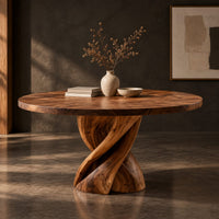 Corner detail of round dining table with a twisted ribbon pedestal beside wood, brass and linen samples