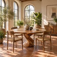 Round dining table on a twisted spiral pedestal base in a bright dining room with arched windows and plants