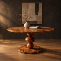 Round dining table with a pedestal of three stacked orbs in a dark studio against a charcoal plaster wall